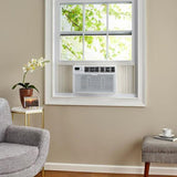 Bevoi 12,000 BTU energy-efficient window air conditioner with remote installed in a living room window.