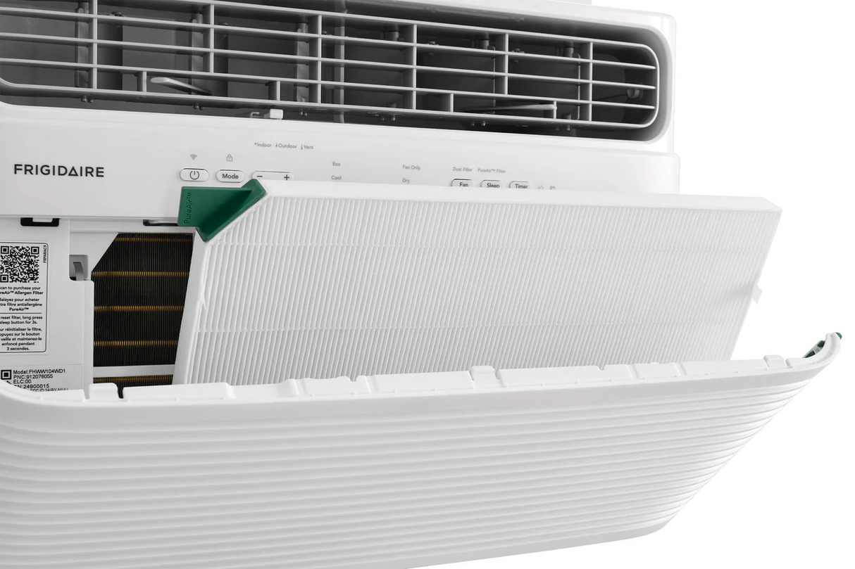 Close-up of a Frigidaire 12,000 BTU Window Room Air Conditioner with Wi-Fi, model FHWV124TE1, with the front panel opened to reveal the white pleated PureAir Advance filter being inserted or removed. A green tab on the filter is visible for easy handling, demonstrating simple maintenance
